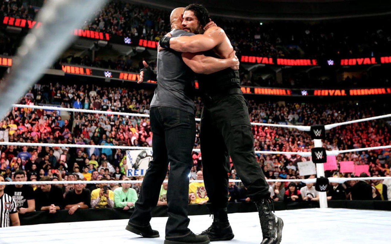 The Rock abraçando seu primo Roman Reigns no ringue da WWE
