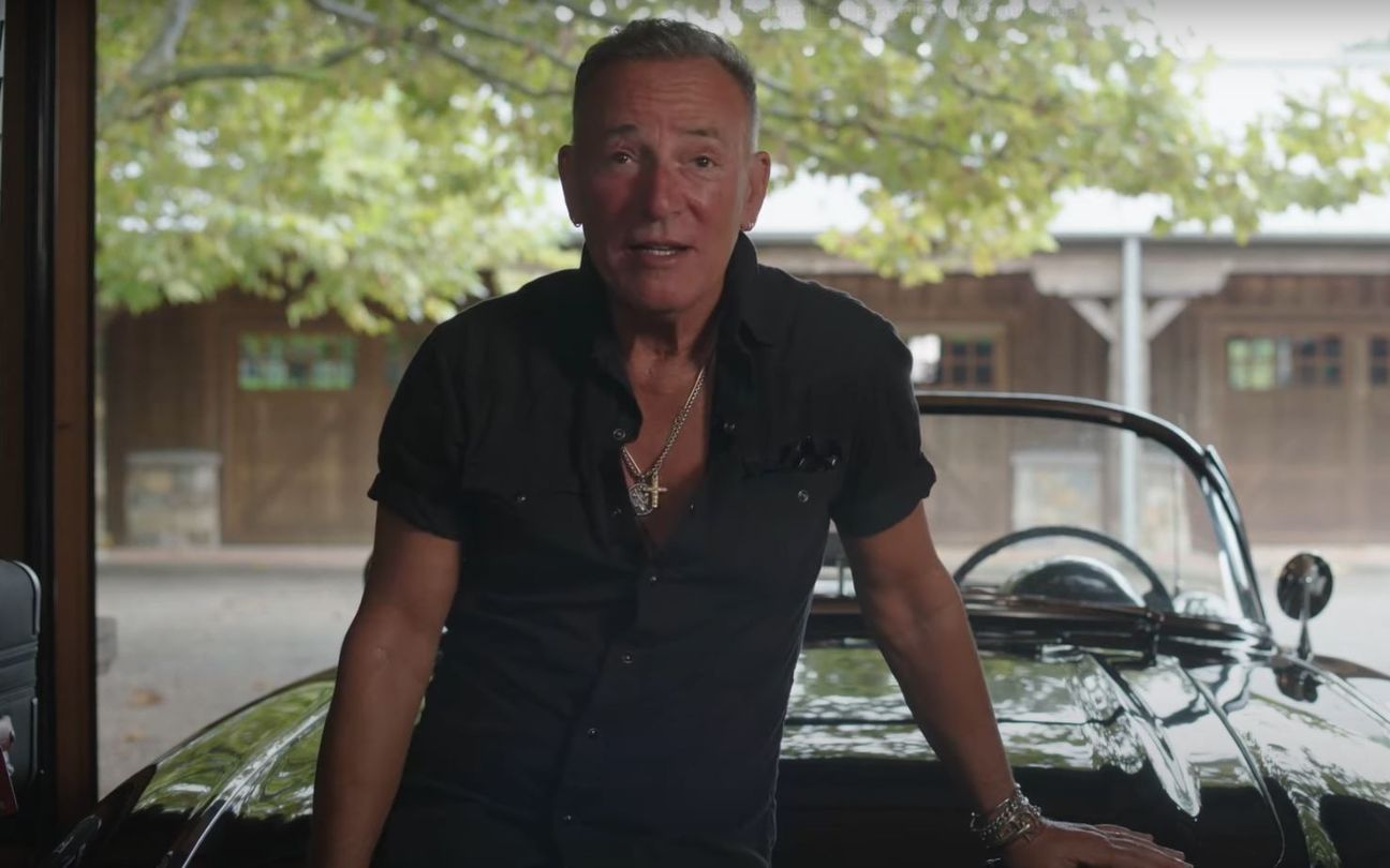 Bruce Springsteen encostado em um carro na garagem